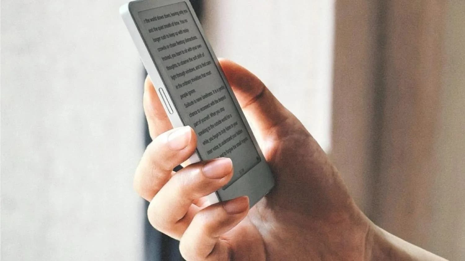 En person håller den lilla e-läsaren Boox Picco med sidknappen synlig